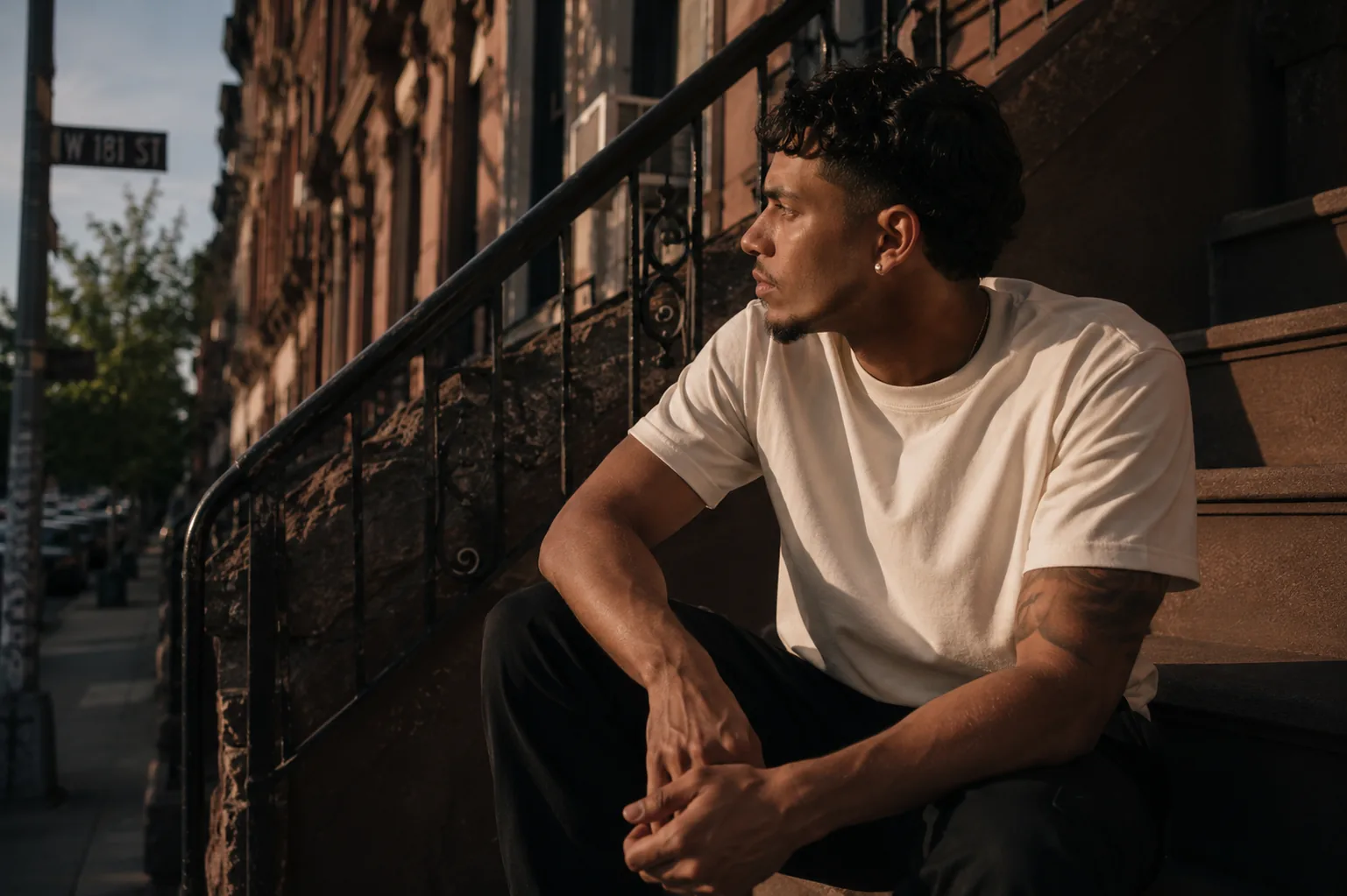 Man in a cream heavyweight tee on a Washington Heights stoop at golden hour